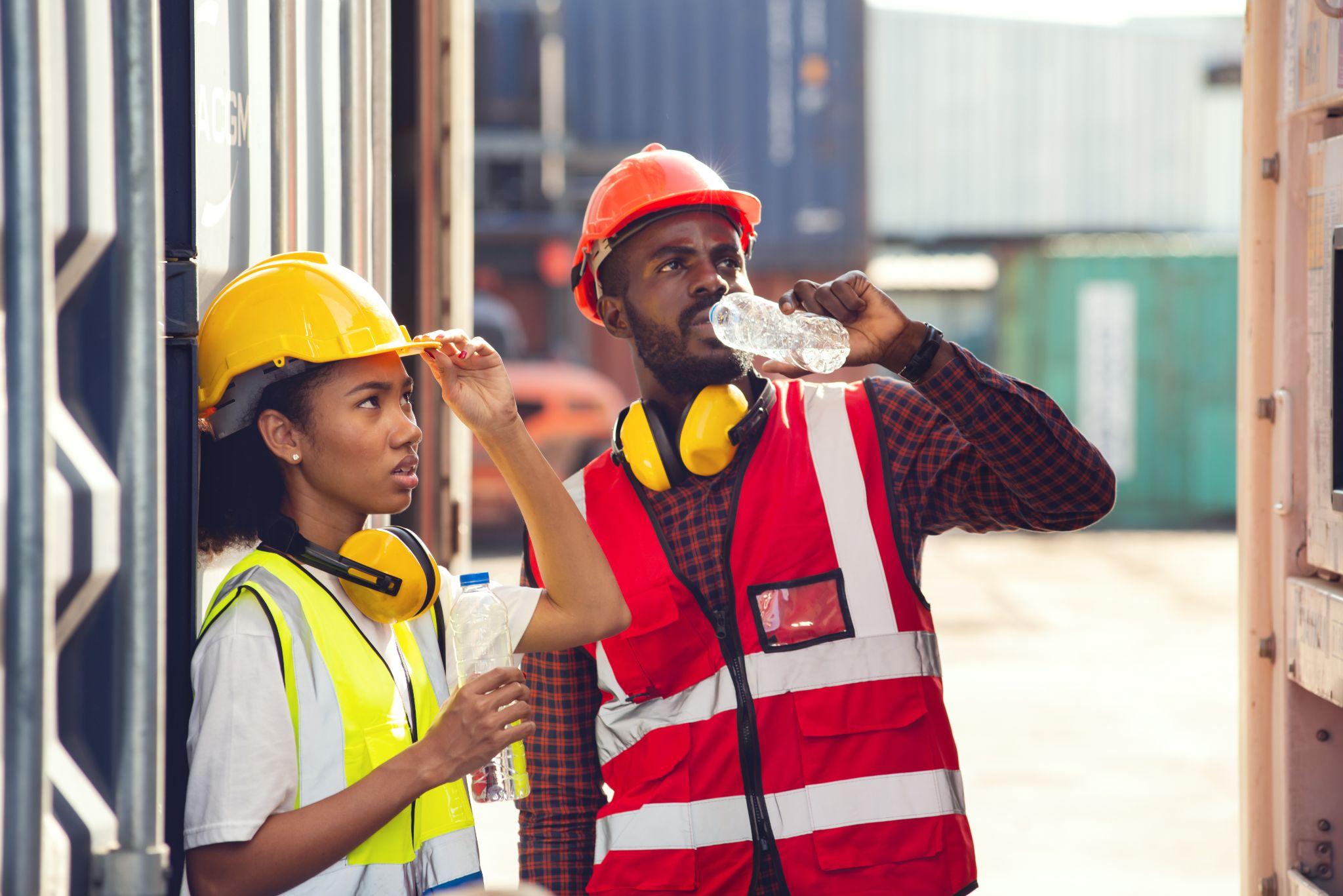 Man and woman technician drinking water and resting after working at container yard