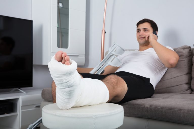 Smiling Young Injured Man Talking On Mobile Phone