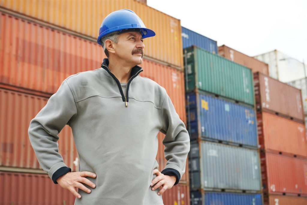 dock worker in front of maritime shipping container