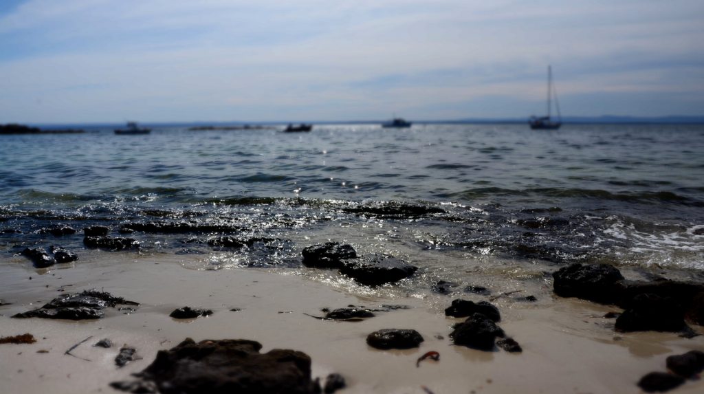 sand beach with soft ocean wave and rocks