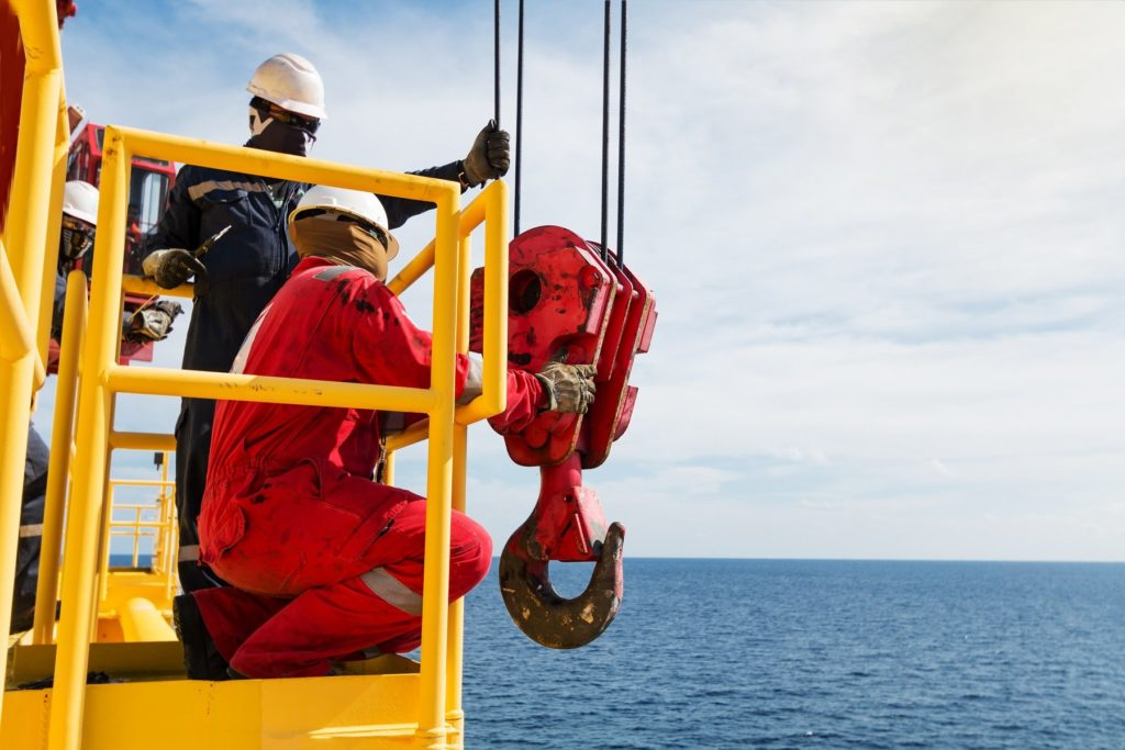 arge workers in safety gear handling rigging on a barge