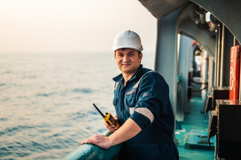 Deck Officer on deck of offshore vessel and holds walkie-talkie radio in hands