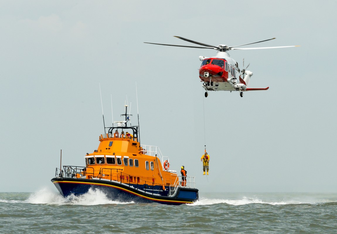 sea rescue boat man being winched to emergency rescue helicopter