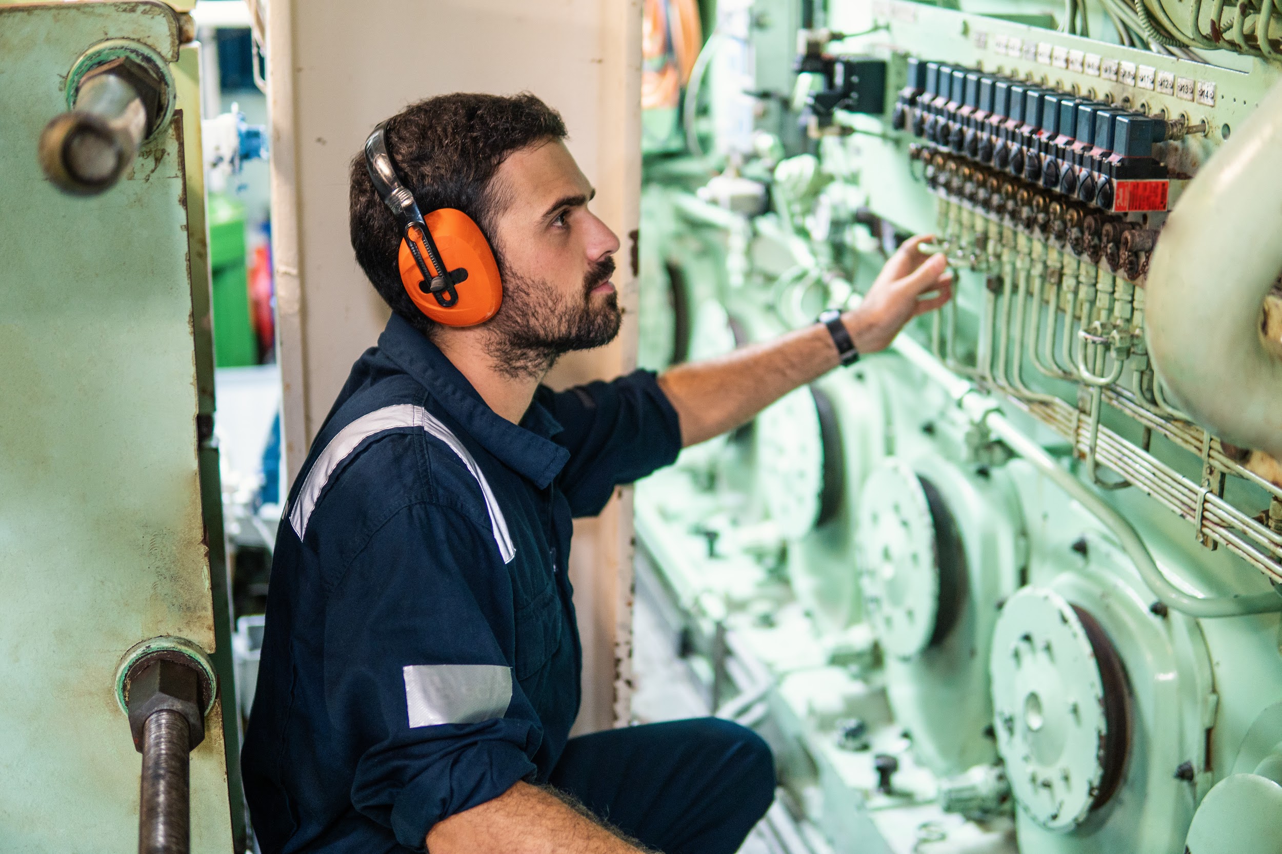 Marine engineer in engine control room, starts or stops main engine of ship