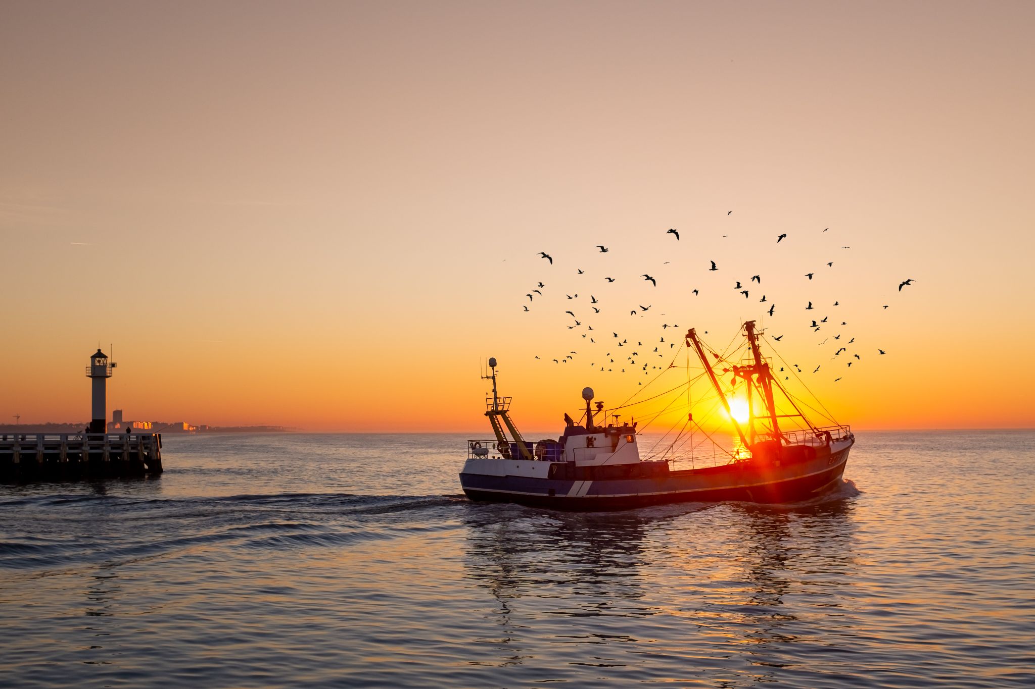 Fishing boat in front of the old wooden pier of Nieuwpoort at sunset