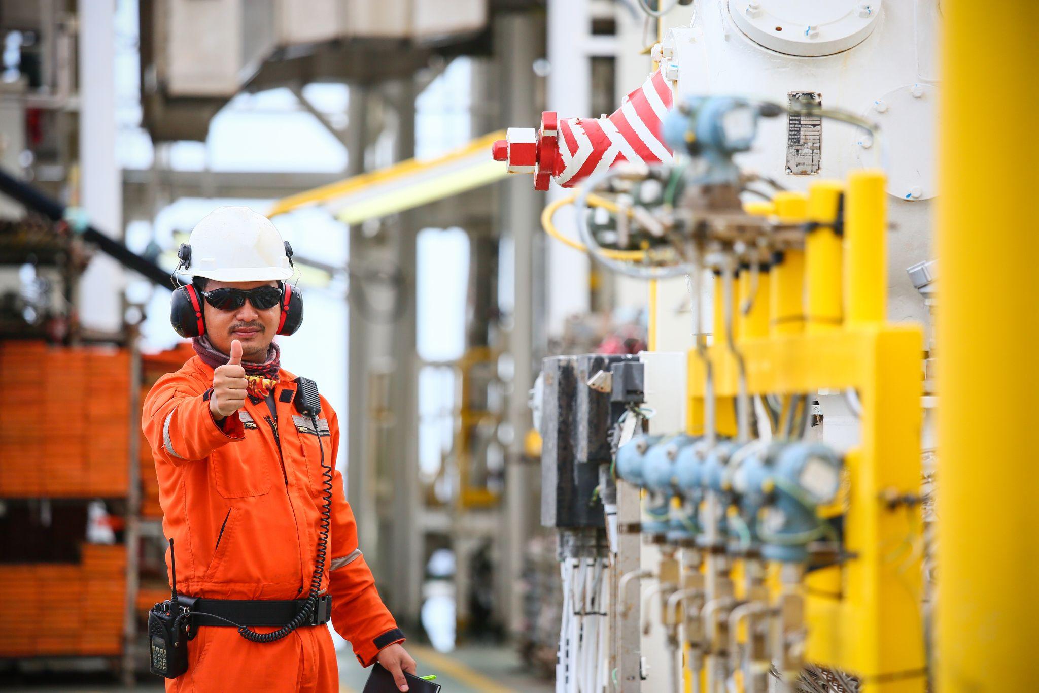 worker recording operation data of oil and gas process at production plant