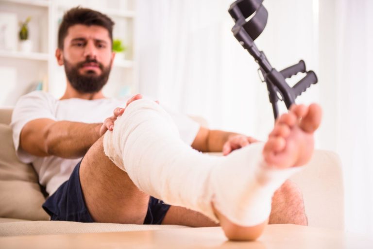 Portrait of a young man with injured leg at home