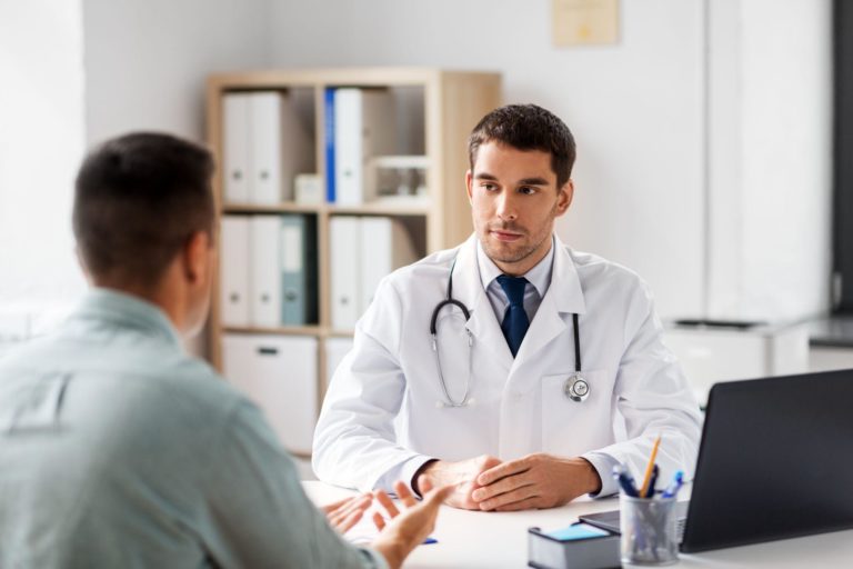 doctor talking to male patient at medical office in hospital