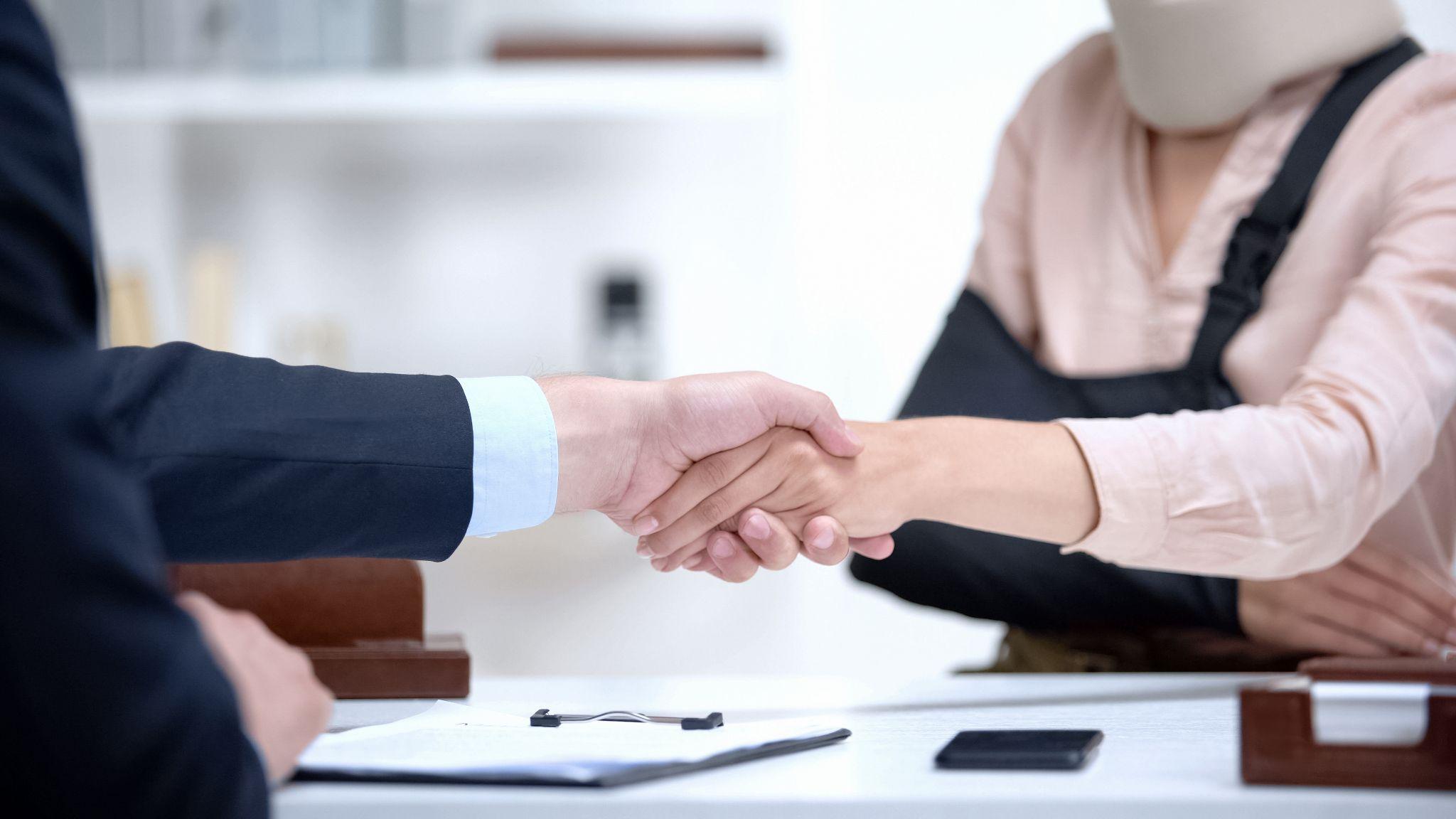 Insurance agent shaking hand with woman in arm sling