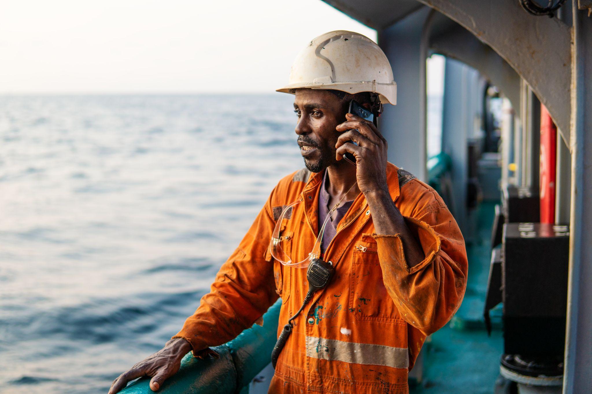 seaman on deck of vessel or ship and speaking on the mobile cell phone