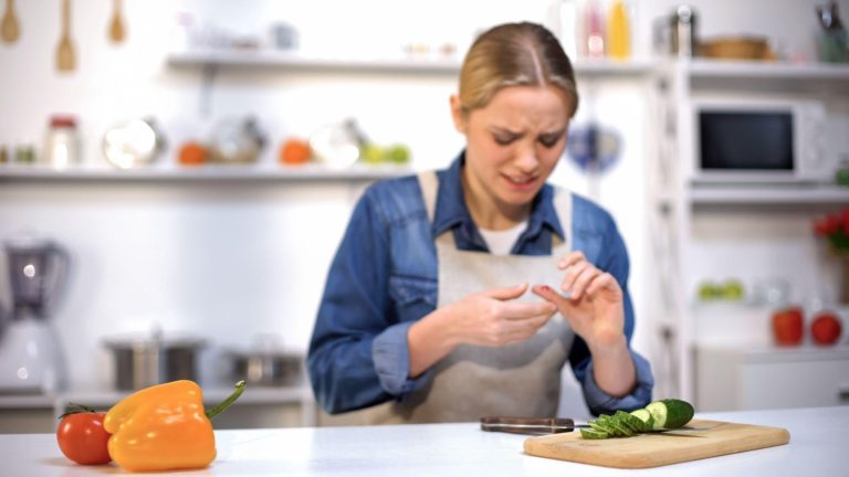 Female cut finger while slicing cucumber, accident in kitchen