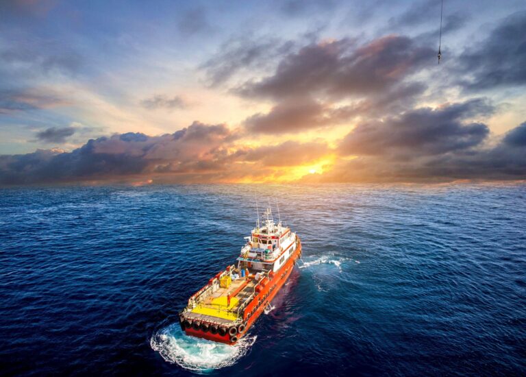 Supply vessel transport cargo for rig platform offshore at sunset.