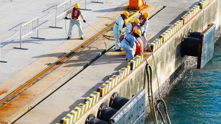 port workers fasten ship mooring ropes to the bollard in the port.