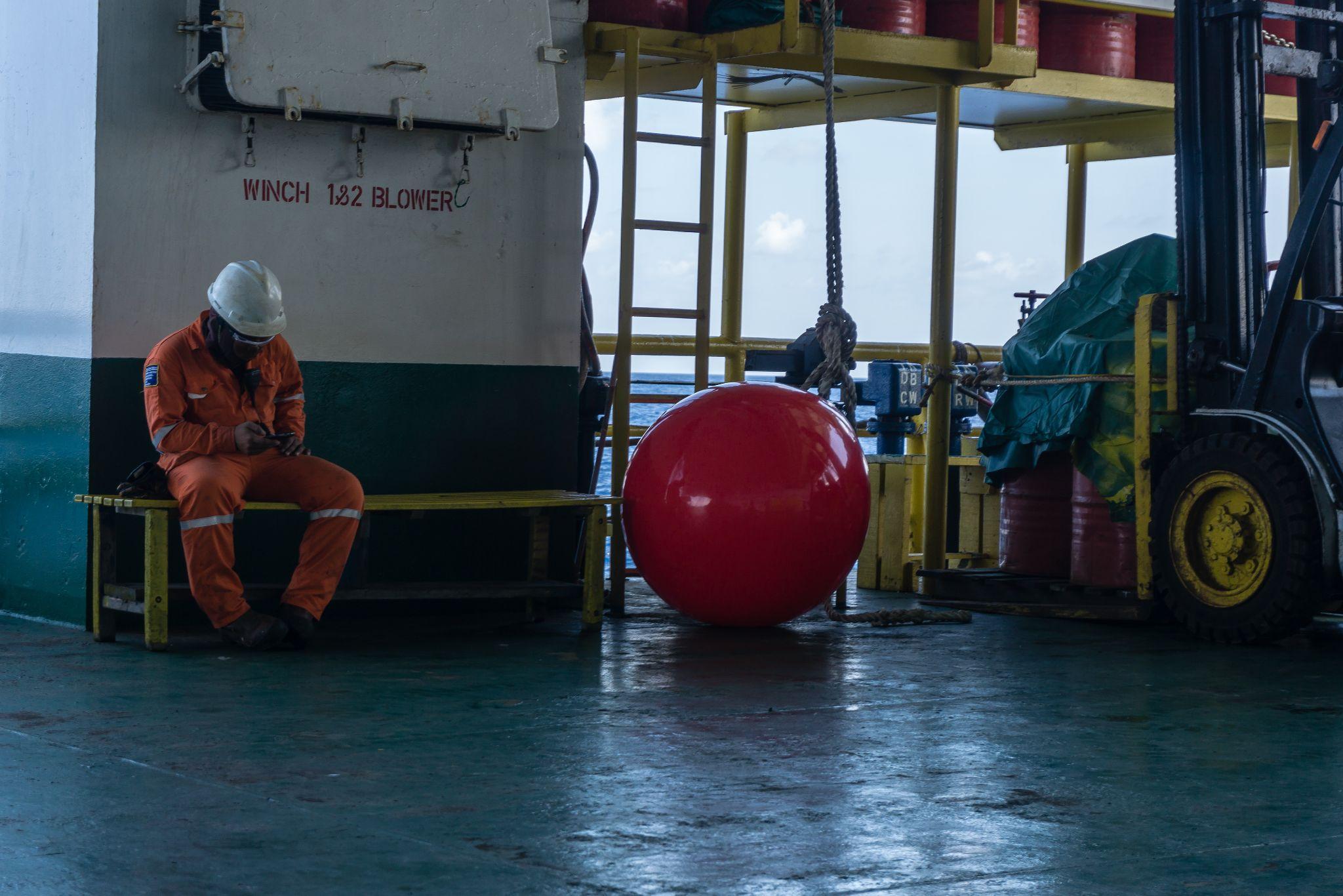 Offshore worker taking rest on a bech on board a construction work barge at oil field