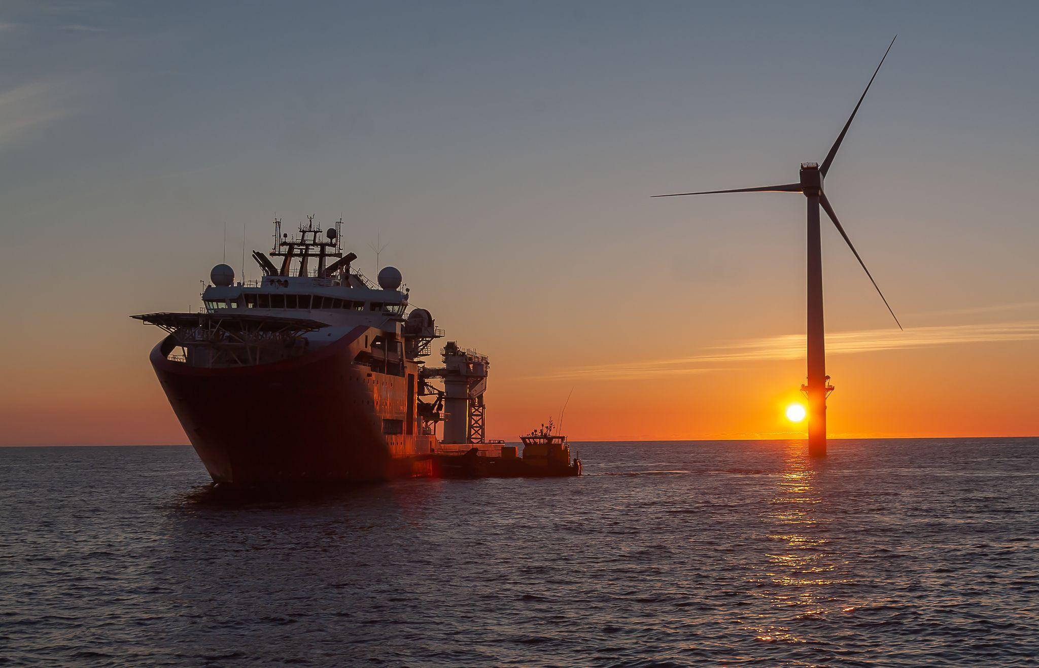 Service operational vesel with crew transfer vessel along side as the sun goes down on the windfarm