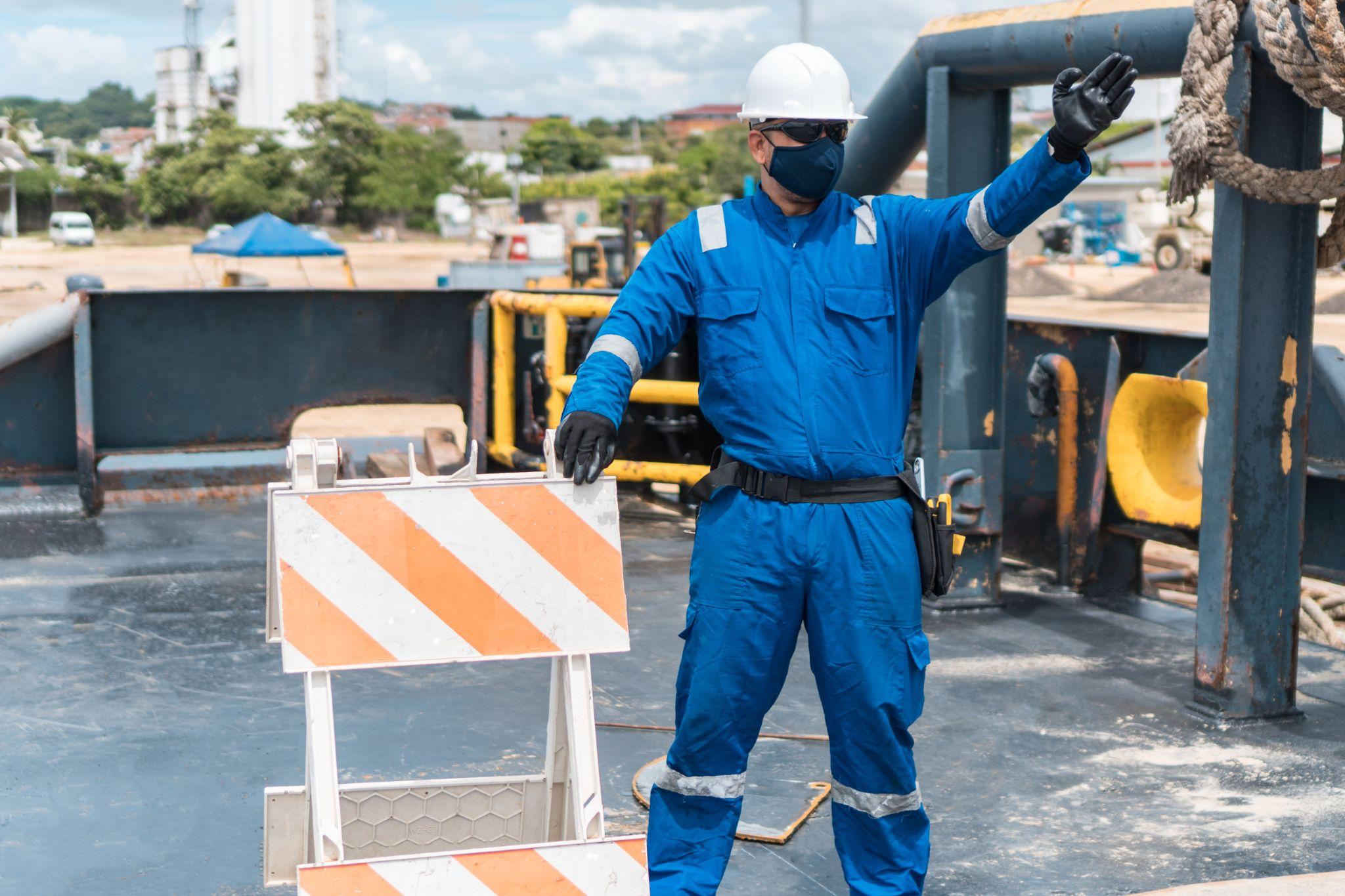 Marine deck officer with protective mask on ship deck pointing with arm