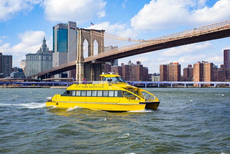 Yellow vessel boat sailing on river near bridge