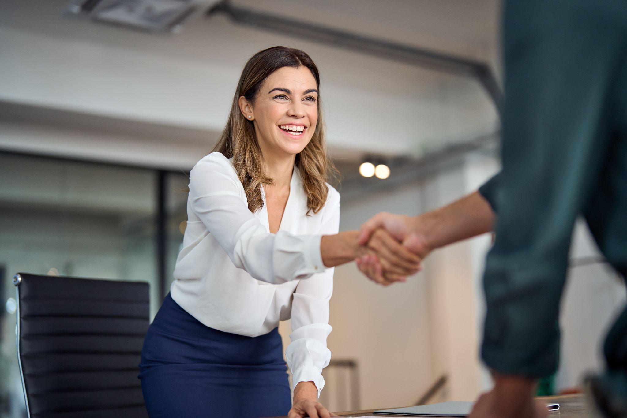 Happy business woman manager handshaking greeting client in office