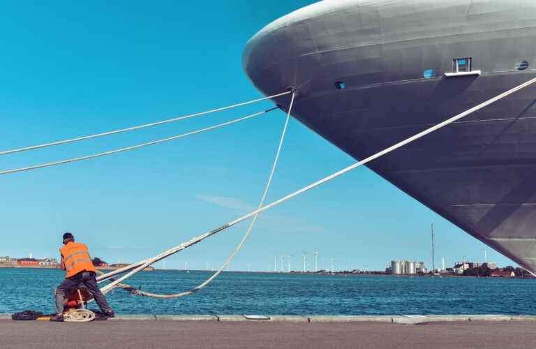 Maritime working pulling a mooring of a large ship to the pier