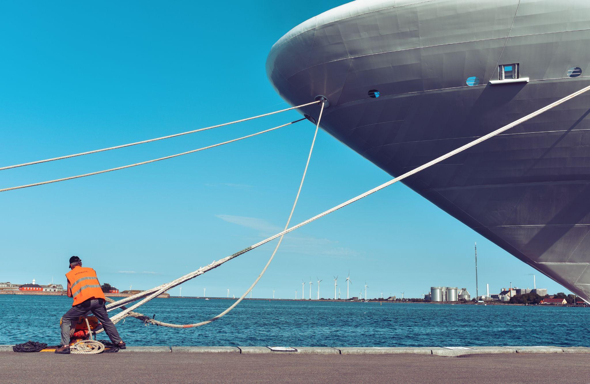 Maritime working pulling a mooring of a large ship to the pier